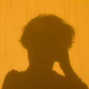 The shadow of a head on an orange wall.